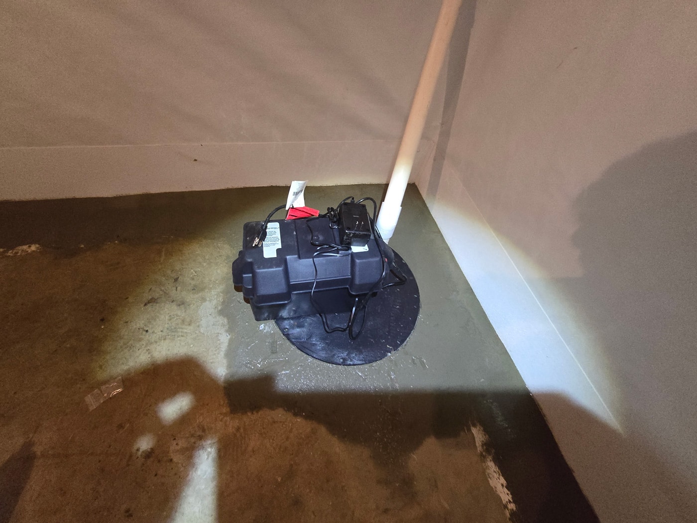 Sump pump installed in a basement corner.