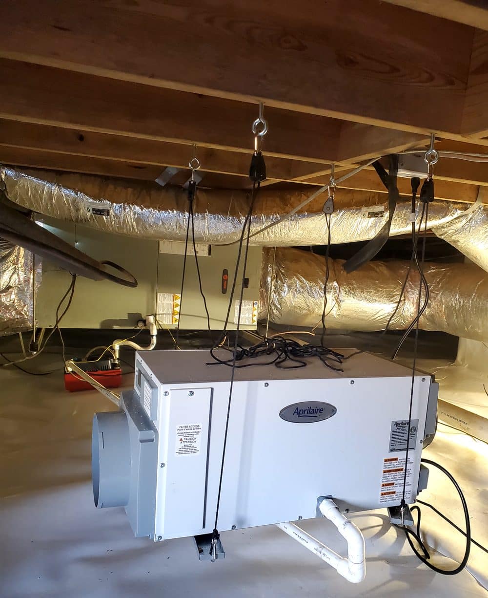 Aprilaire dehumidifier installed in basement with ductwork and cables.