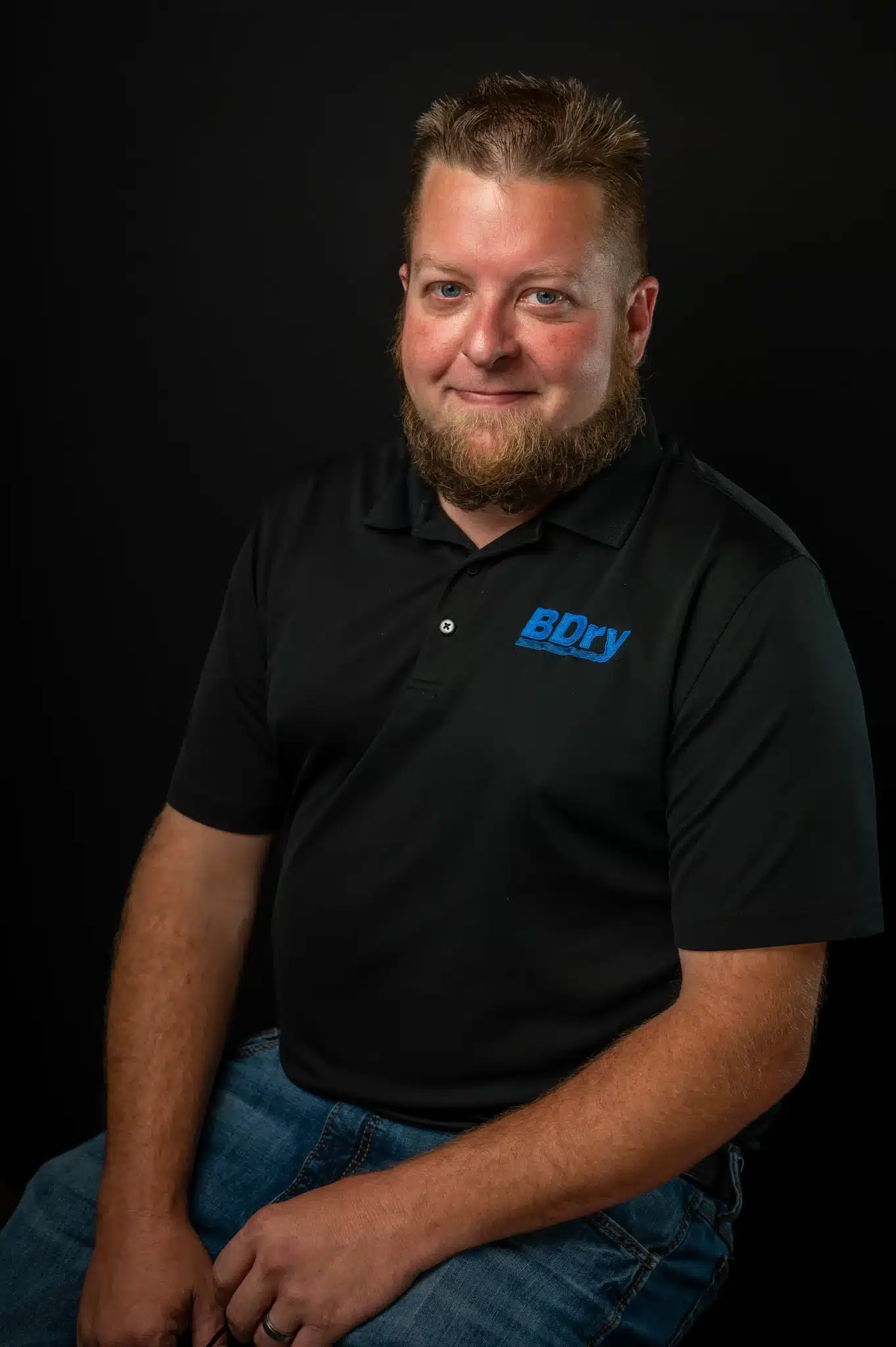 Man in black polo shirt with BDRY logo against a dark background.