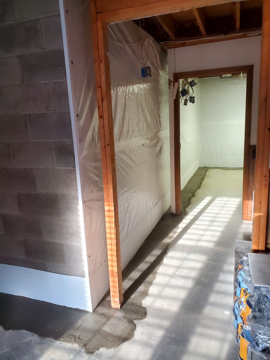Construction area with plastic-covered walls and unfinished floor.