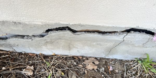 A wide crack splitting a sunken concrete driveway slab — a clear sign the slab needs poly lifting repair.